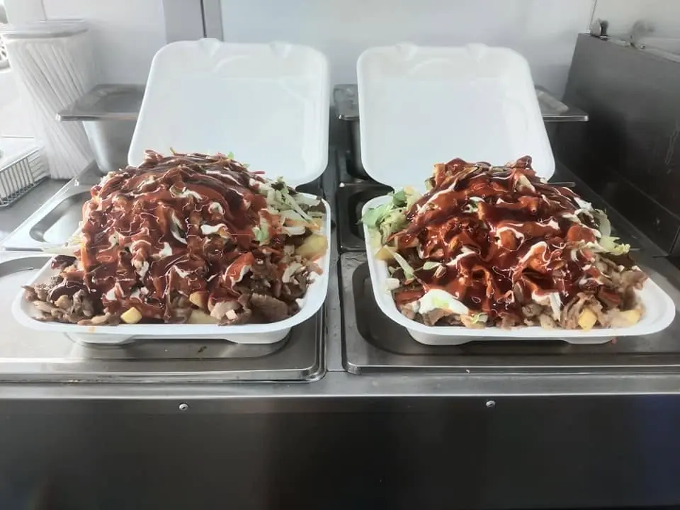 Two takeaway snack packs topped with meat and sauces